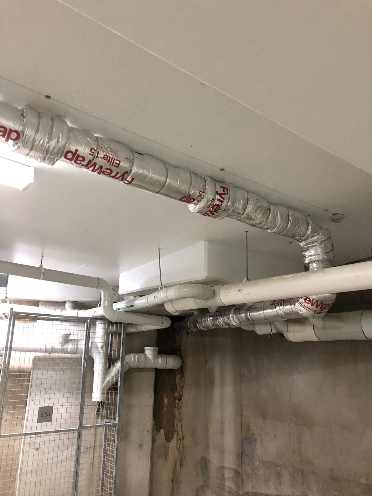 Overhead FyreWrap-clad ductwork in a basement carpark, rectified to comply with AFSS for a Sydney building owner